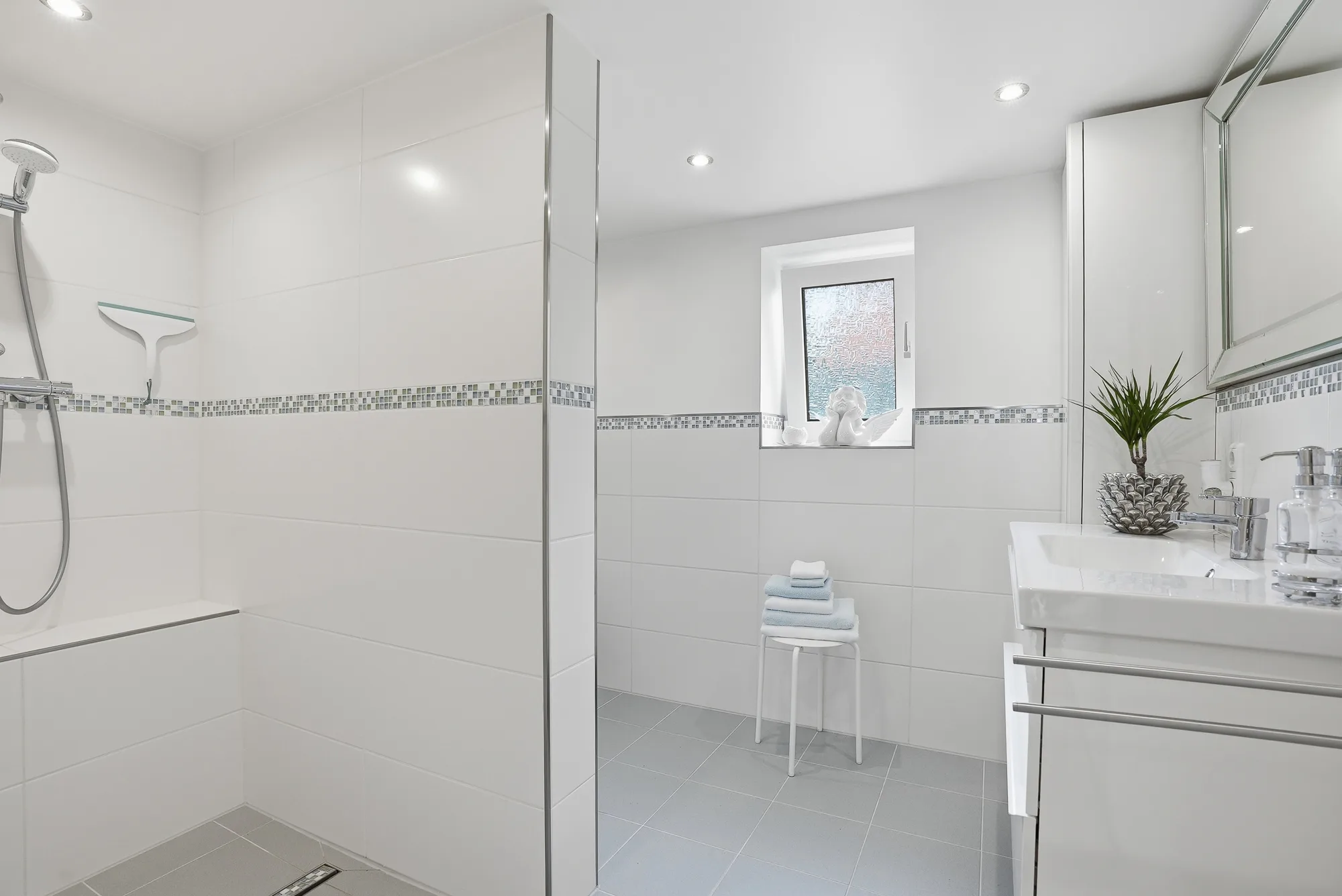 Helles Badezimmer mit bodengleicher Dusche und Fenster
