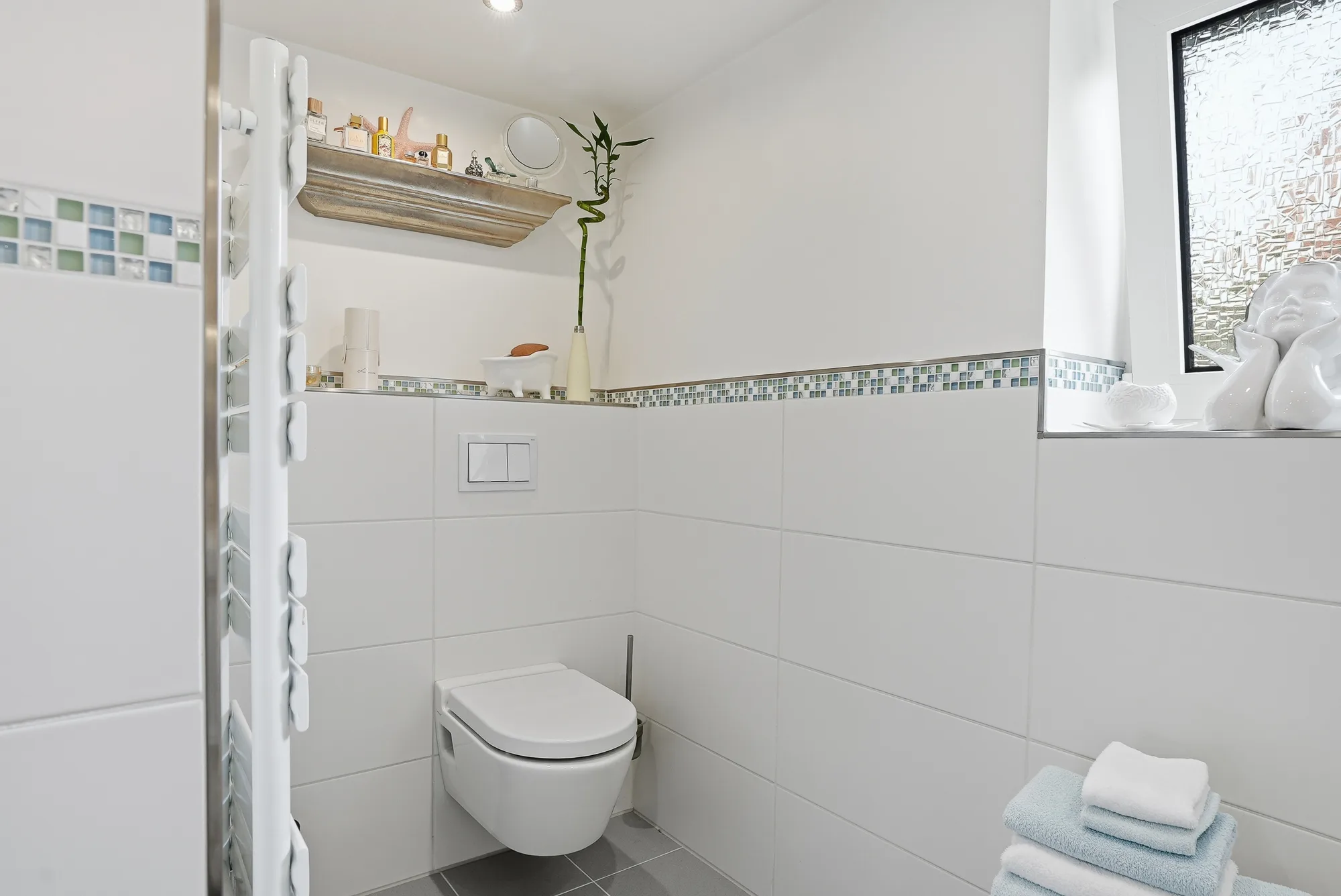 Gäste-Bad mit Wand-WC und heller Fliesengestaltung